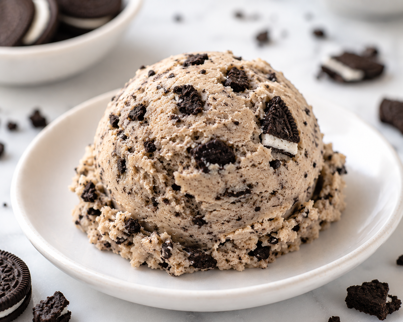 A generous scoop of Cookies & Cream cookie dough with sandwich-cookie pieces on a ceramic plate